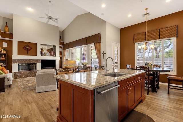 kitchen with a premium fireplace, sink, light hardwood / wood-style flooring, and a kitchen island with sink