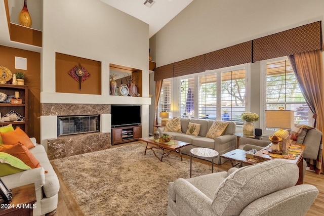 living room featuring hardwood / wood-style floors, high vaulted ceiling, and a high end fireplace