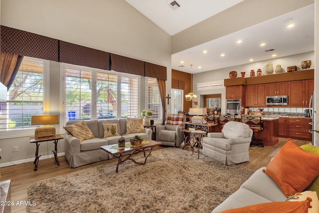 living room with light hardwood / wood-style floors, high vaulted ceiling, and a chandelier