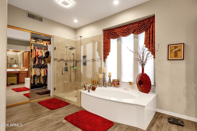 bathroom with shower with separate bathtub and wood-type flooring