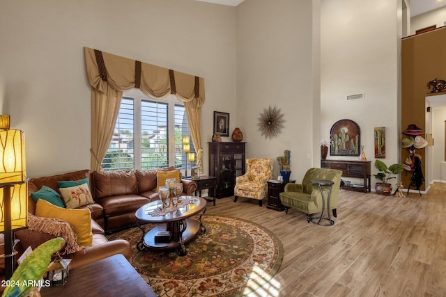 living room featuring a towering ceiling and light wood-type flooring