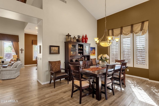 dining area featuring high vaulted ceiling, wood-type flooring, and an inviting chandelier