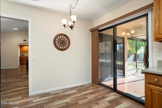 interior space with wood-type flooring, lofted ceiling, and a notable chandelier