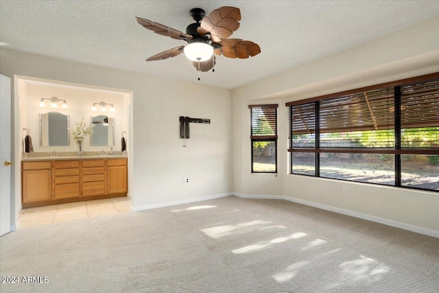 unfurnished bedroom featuring a textured ceiling, light carpet, ceiling fan, and connected bathroom