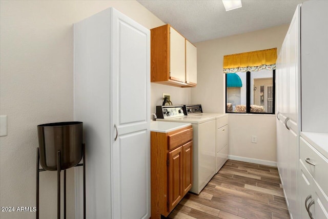 laundry area with cabinets, separate washer and dryer, a textured ceiling, and light hardwood / wood-style flooring