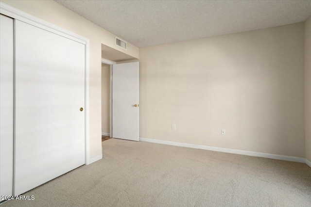 unfurnished bedroom with a textured ceiling, a closet, and carpet floors