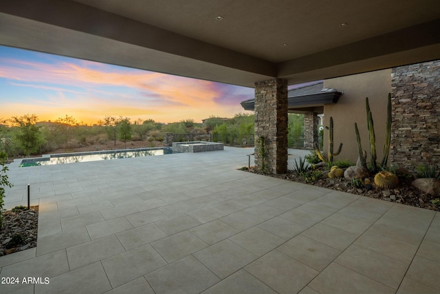 patio terrace at dusk featuring a swimming pool with hot tub