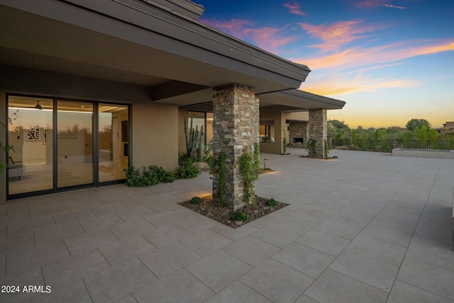 patio terrace at dusk featuring a fireplace