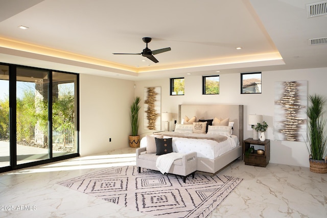 bedroom with ceiling fan, a raised ceiling, and multiple windows