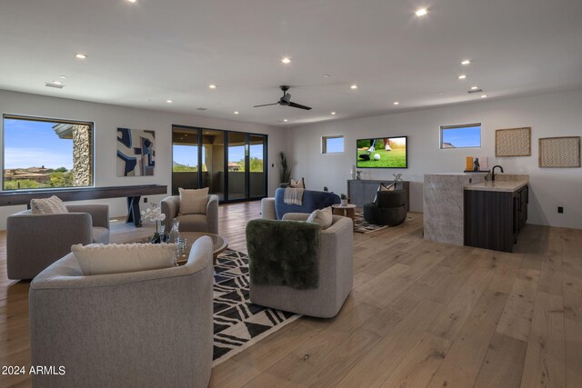 living room featuring sink, ceiling fan, and light hardwood / wood-style flooring