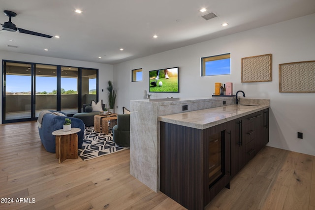 kitchen with dark brown cabinetry, sink, light hardwood / wood-style floors, and kitchen peninsula