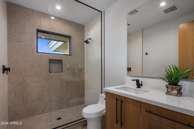 bathroom featuring tiled shower, vanity, and toilet