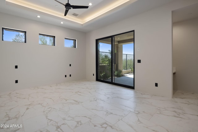 empty room with a raised ceiling and ceiling fan