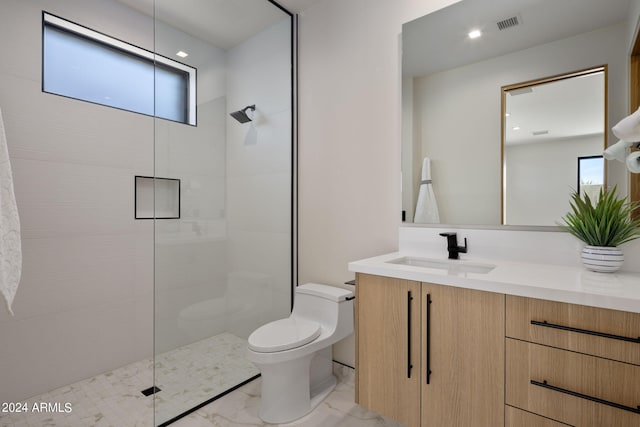 bathroom featuring vanity, toilet, a shower with shower door, and plenty of natural light