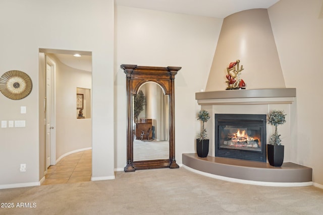 unfurnished living room with a towering ceiling, a fireplace, and light carpet