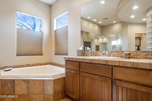 bathroom with vanity and a relaxing tiled tub