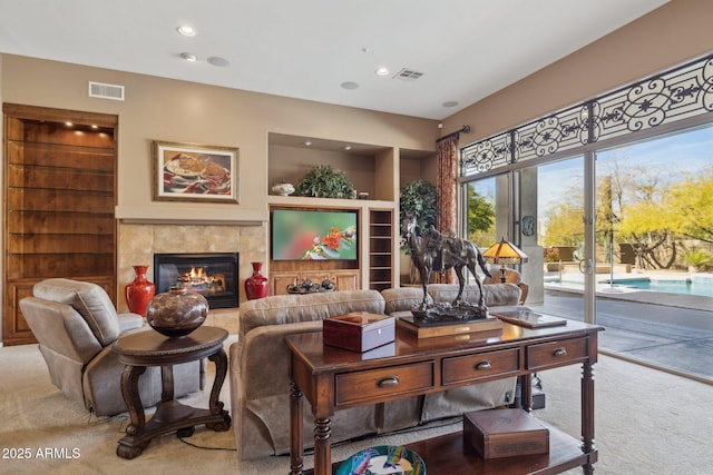 living room with built in shelves, carpet floors, and a tile fireplace