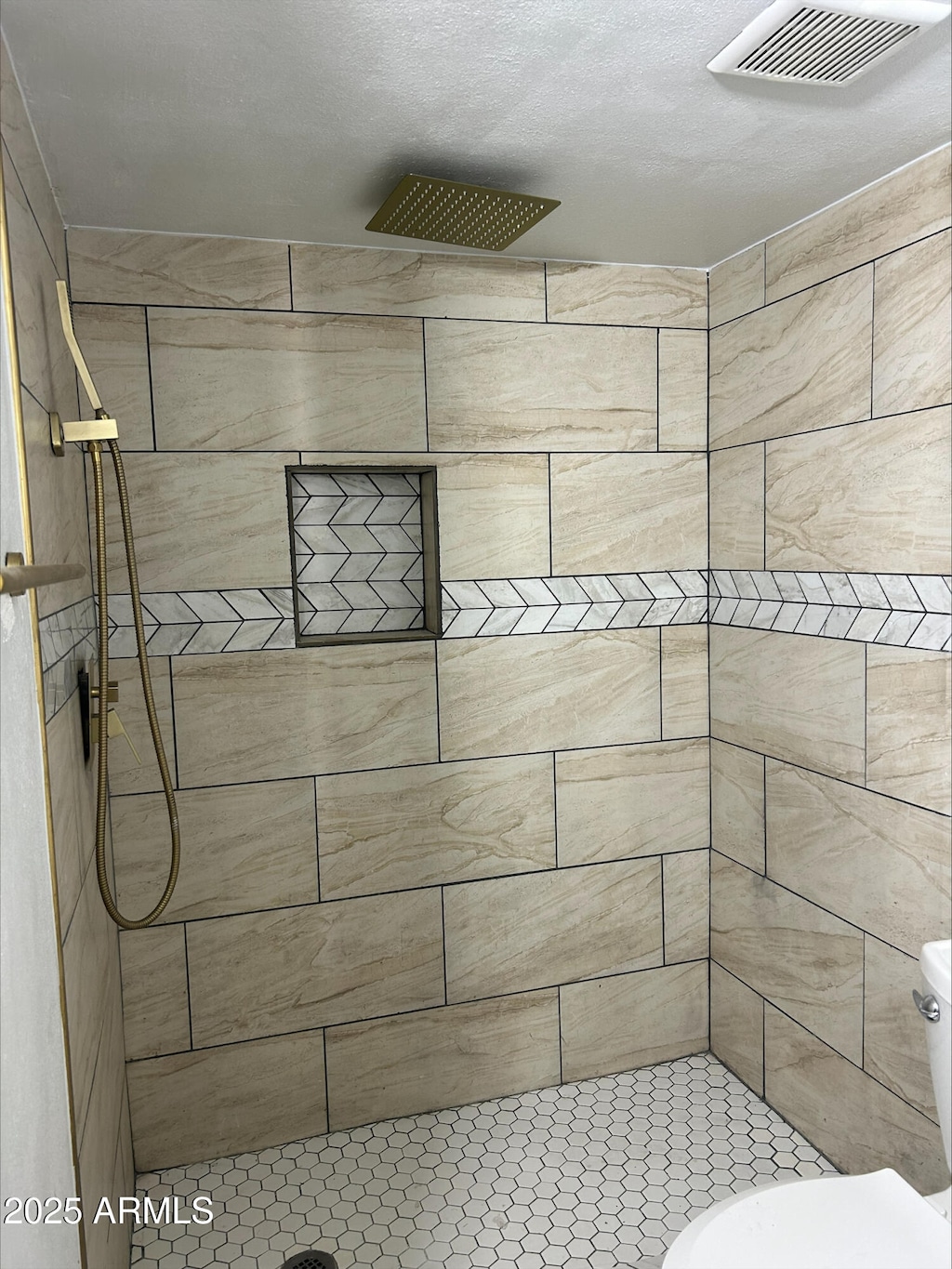 full bath with toilet, visible vents, and tiled shower
