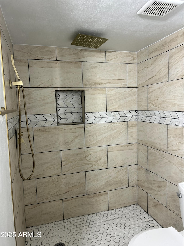 full bath with toilet, visible vents, and tiled shower