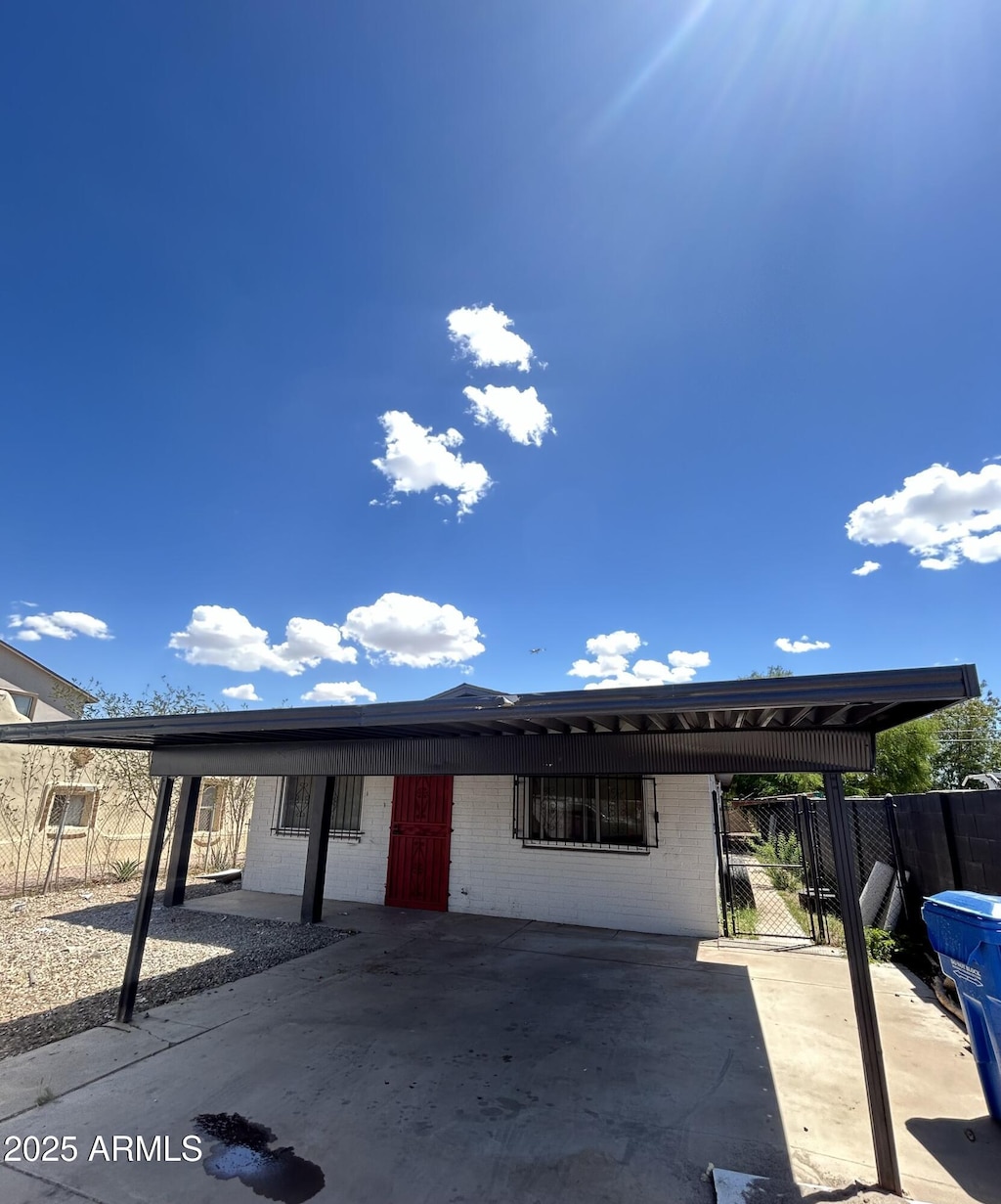 view of front of house with fence, an attached carport, and brick siding