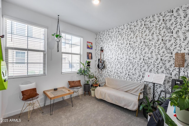 sitting room with wallpapered walls, an accent wall, baseboards, and carpet