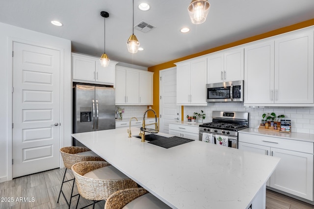 kitchen featuring white cabinets, appliances with stainless steel finishes, a sink, and visible vents