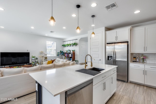 kitchen with a sink, visible vents, open floor plan, and stainless steel appliances