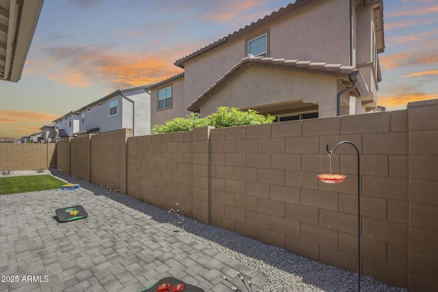 property exterior at dusk with a fenced backyard, stucco siding, and a patio area