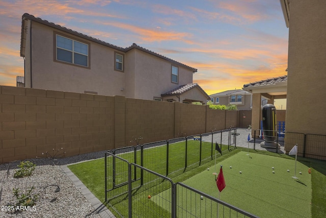 yard at dusk featuring a fenced backyard