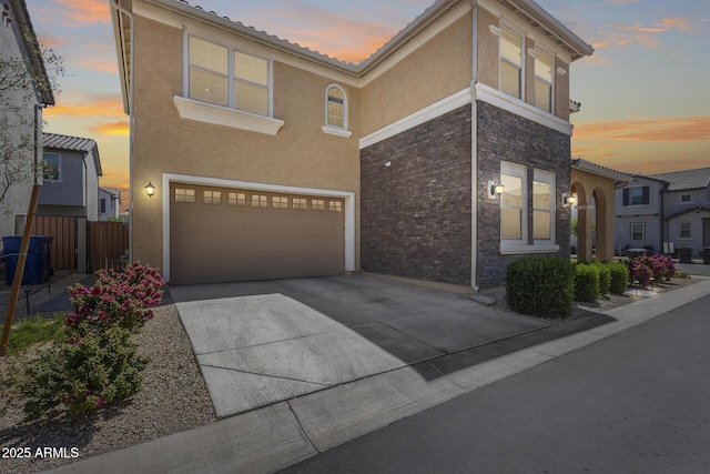 view of front of house featuring a tiled roof, a garage, concrete driveway, fence, and stucco siding