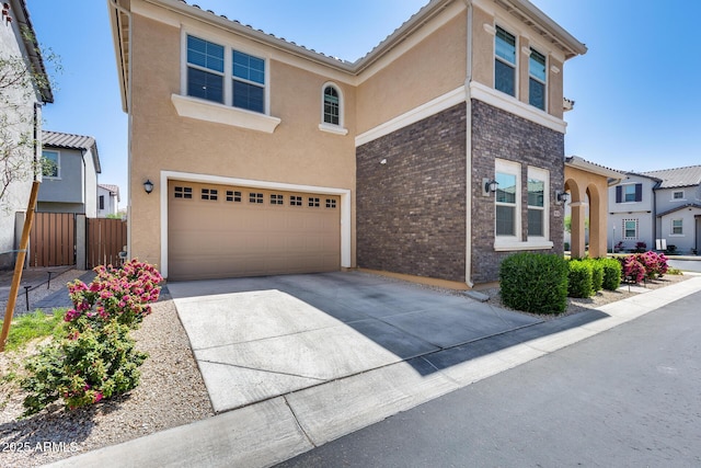traditional-style house with driveway, fence, a garage, and stucco siding