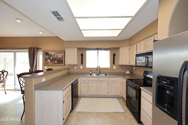 kitchen featuring visible vents, light brown cabinetry, a sink, a peninsula, and black appliances