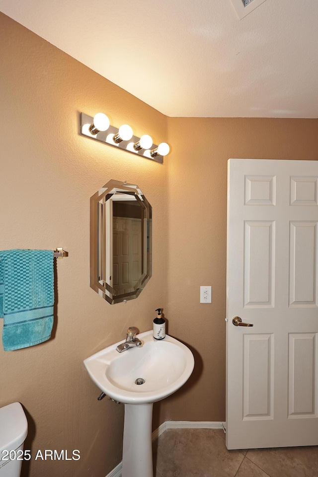 bathroom featuring toilet, baseboards, and tile patterned floors