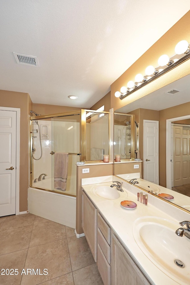 bathroom featuring shower / bath combination with glass door, visible vents, a sink, and tile patterned floors