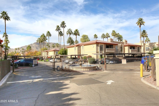 view of front of house featuring a gate, a mountain view, uncovered parking, and fence