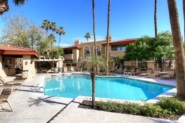 community pool with a patio area and fence