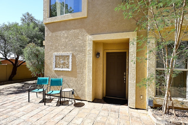 property entrance featuring a patio, fence, and stucco siding