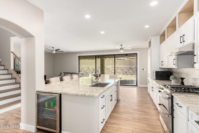 kitchen featuring wine cooler, double oven range, a ceiling fan, and a sink
