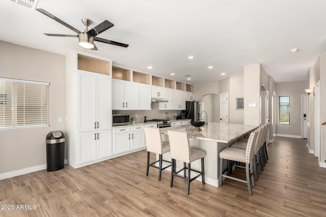 kitchen with light wood finished floors, appliances with stainless steel finishes, baseboards, and arched walkways
