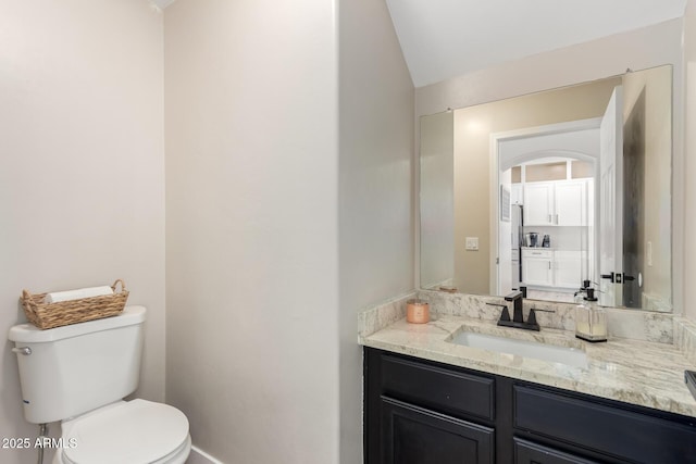 half bath with lofted ceiling, toilet, baseboards, and vanity