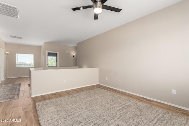 empty room featuring baseboards, visible vents, light wood-style flooring, and a ceiling fan