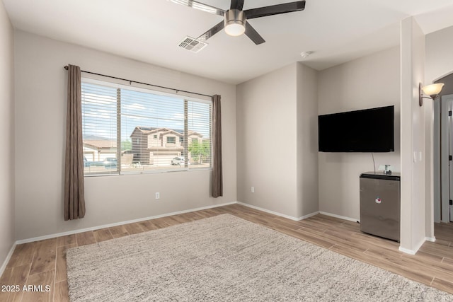 unfurnished living room featuring light wood finished floors, visible vents, baseboards, and ceiling fan
