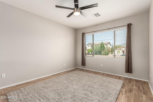 spare room with light wood-style flooring, baseboards, a ceiling fan, and visible vents