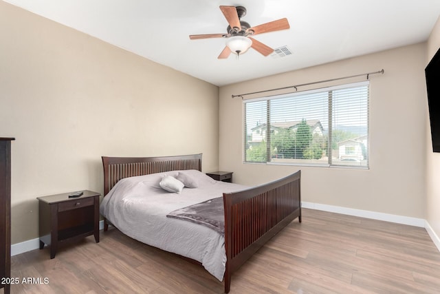 bedroom with visible vents, wood finished floors, baseboards, and ceiling fan