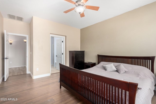bedroom featuring ceiling fan, baseboards, visible vents, and wood finished floors