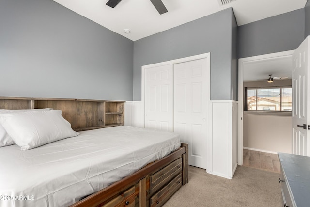 bedroom featuring light colored carpet, a closet, and a ceiling fan