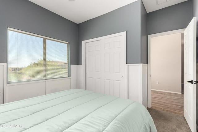 carpeted bedroom with a closet and a wainscoted wall