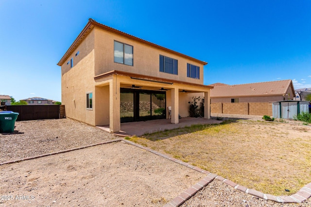 rear view of house featuring stucco siding, a fenced backyard, a ceiling fan, and a patio area