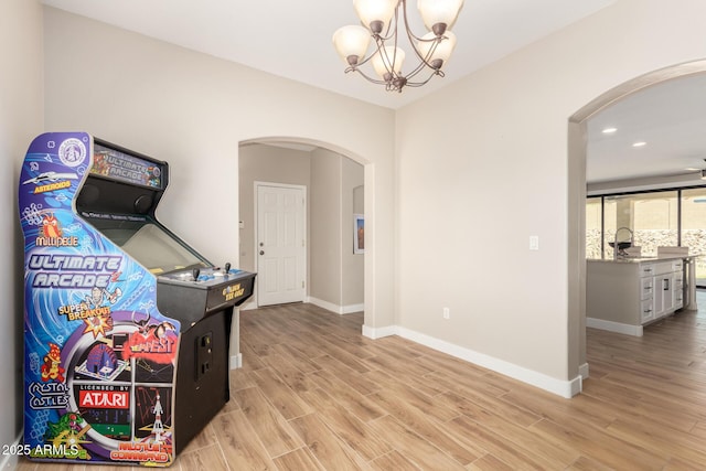 game room featuring arched walkways, baseboards, light wood-style flooring, and recessed lighting