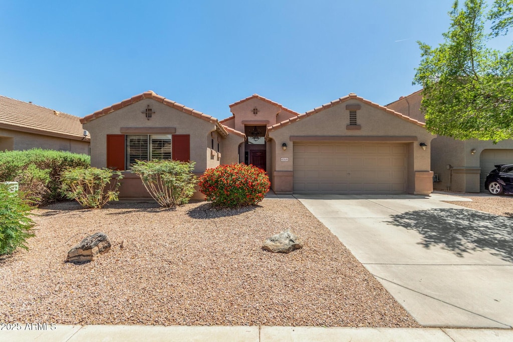 mediterranean / spanish-style home with an attached garage, driveway, a tile roof, and stucco siding
